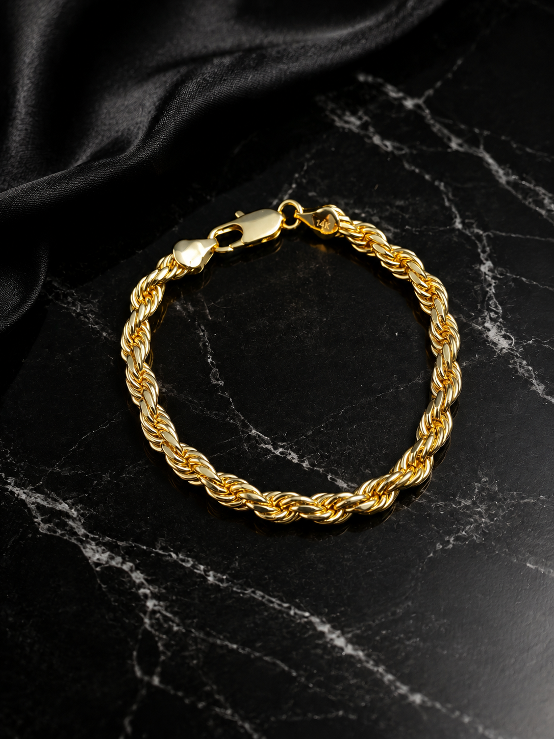 14K gold plated rope chain bracelet arranged in a circle on black marble