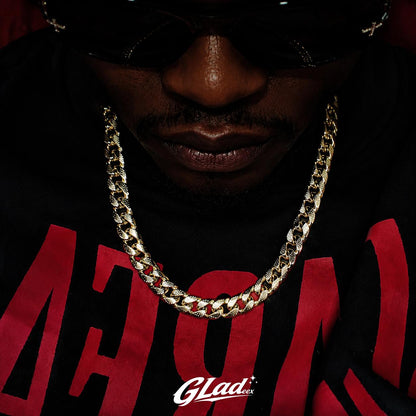 Man wearing an 8mm gold plated Cuban link chain over a black and red shirt