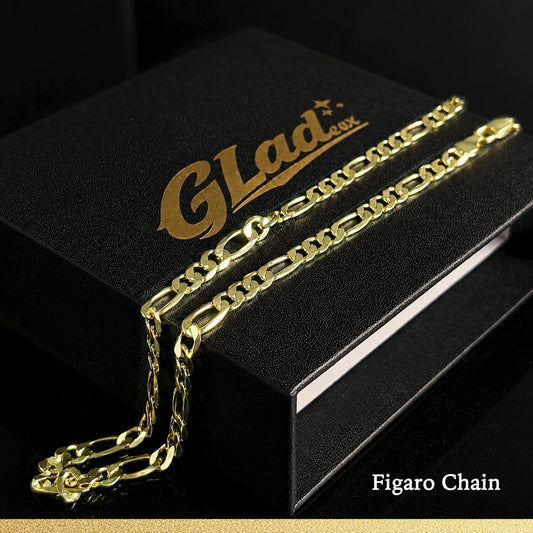 14K gold plated Figaro chain draped across a black GLADEEX presentation box