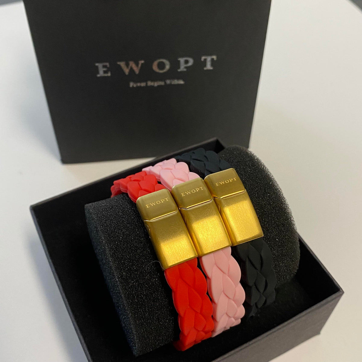 Red, pink and black silicone bracelets with gold plated clasps inside a gift box